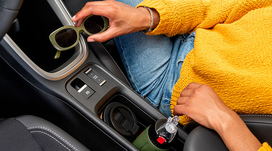 Woman putting sunglasses into the center console of a Jeep Avenger