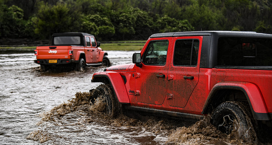 Red Jeep Gladiator driving through water